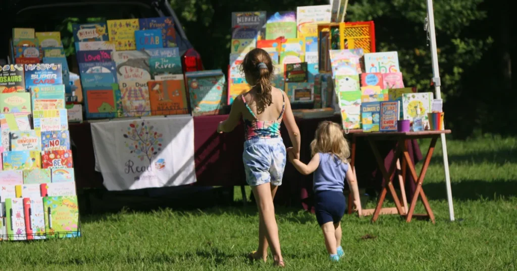 Kinder laufen auf einen Verkaufsstand mit Kinderbüchern zu.